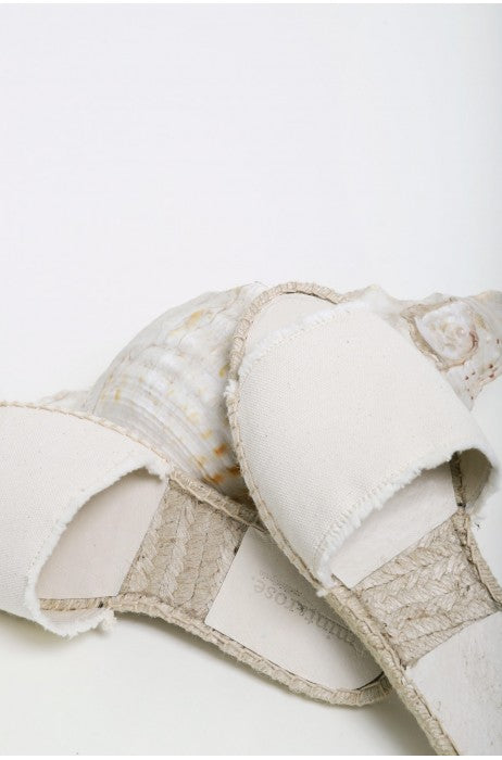 Photo sur fond blanc et zoomée  de mules plates pour femme beiges en coton et fabriquées en Espagne.