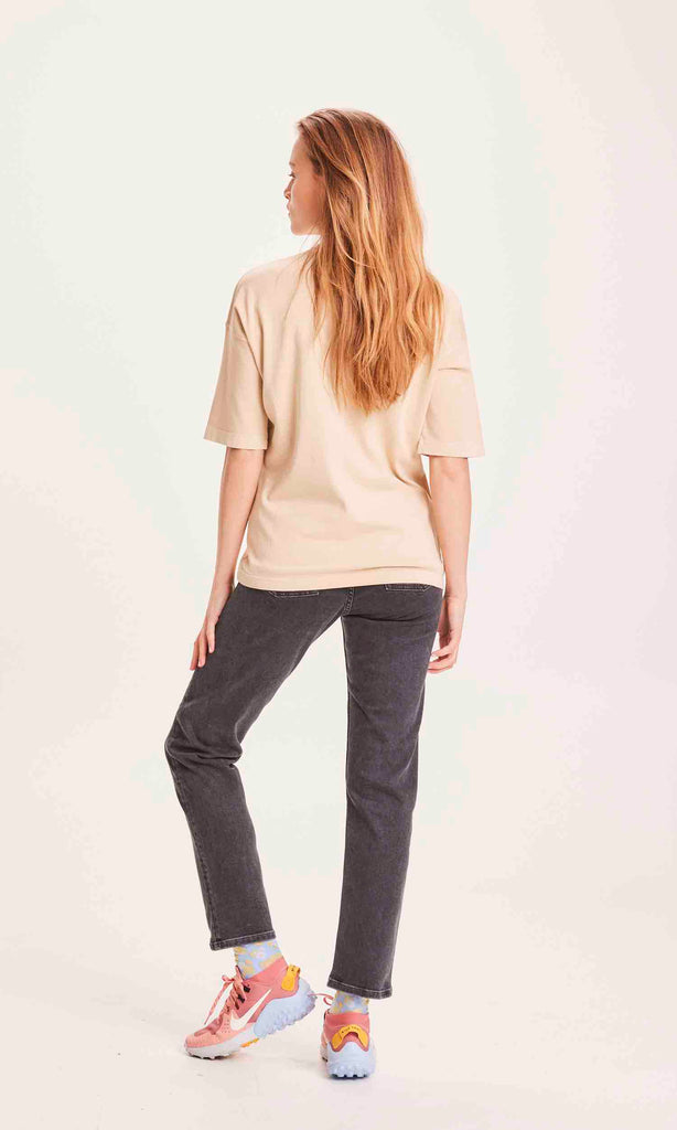 Une femme de dos porte un jean Mom gris foncé de la marque Knowledge Cotton Apparel.