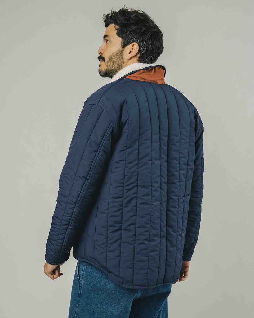 Un homme de dos  porte un manteau bleu marine matelassé de la marque Brava Fabrics.