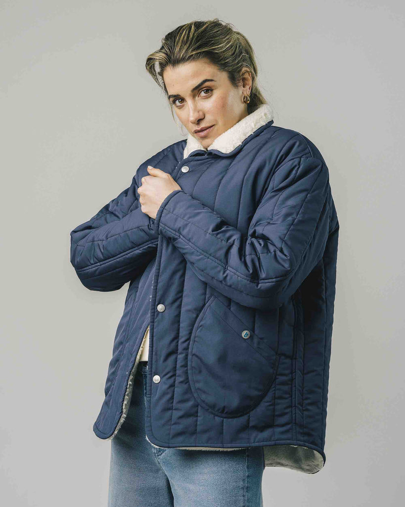 Une femme porte un manteau bleu marine matelassé de la marque Brava Fabrics.