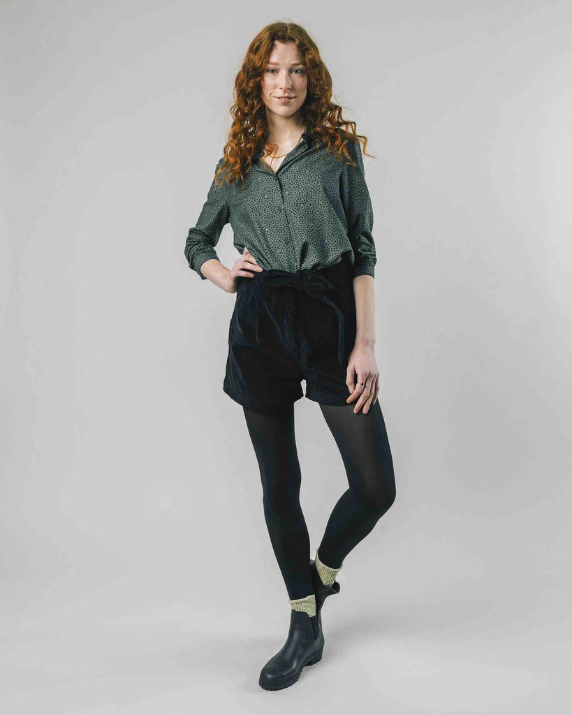 Une femme porte un short en velour noir avec ceinture de la marque Brava Fabrics.