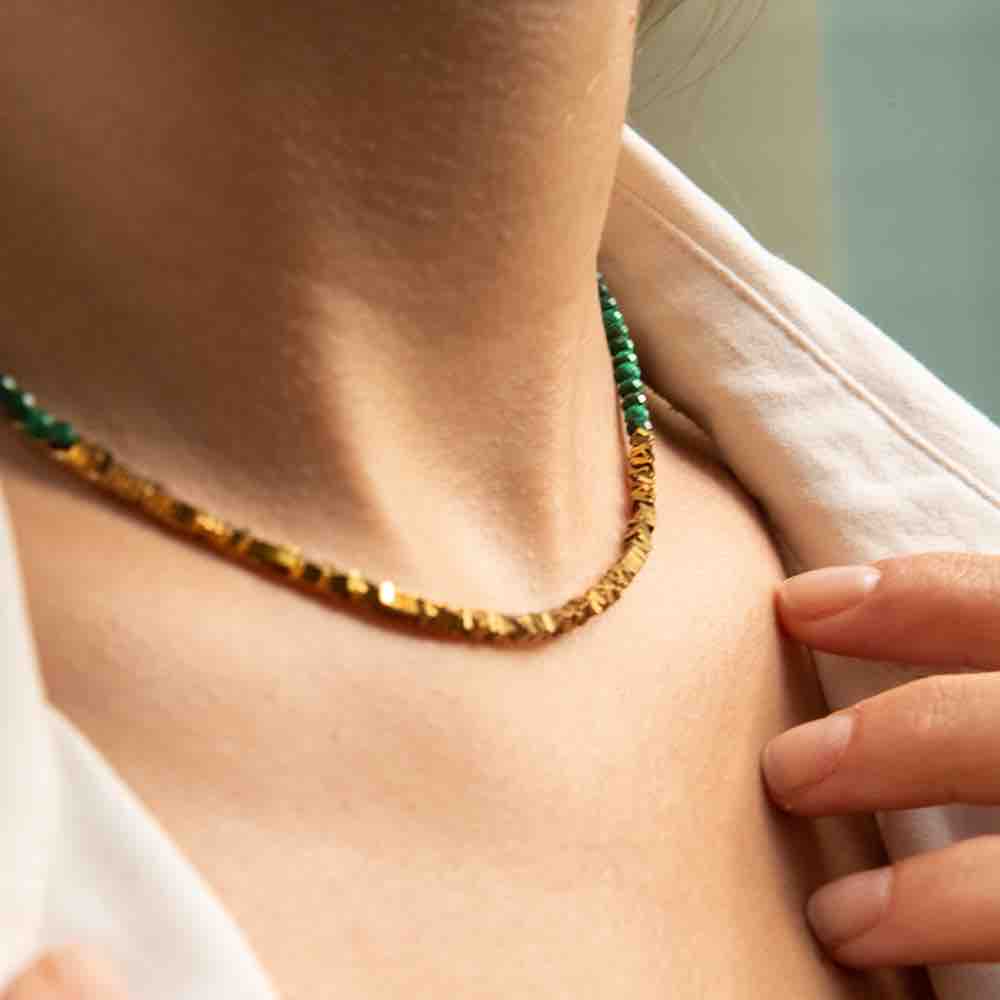Une femme porte le bracelet Myriade Choker en mode collier avec pierres naturelles de malachite de la marque Aura Bijoux.