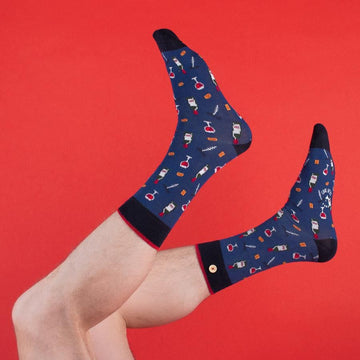Photo sur fond rouge de chaussettes originales homme avec des verres de vin imprimés et en coton bio de la marque cabaia.