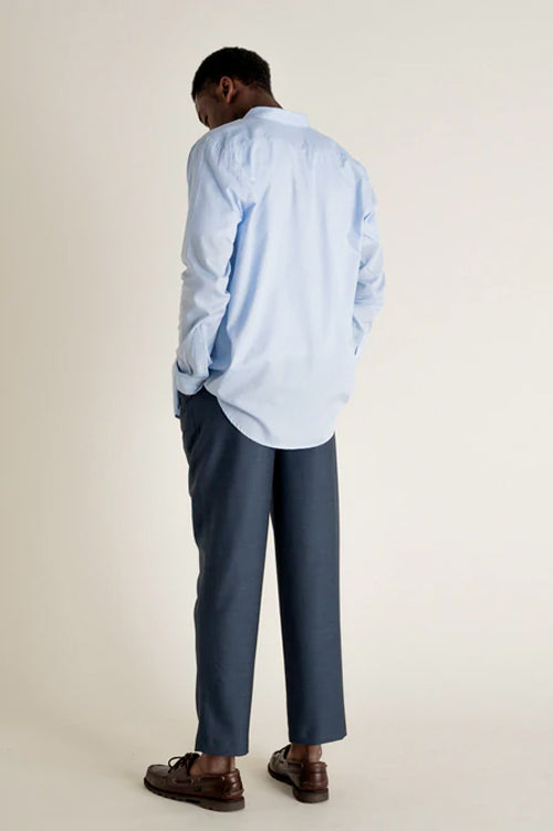 Photo d'un mannequins de dos portant une chemise unie mixte en bleu en coton upcyclé et fabriquée en Roumanie.