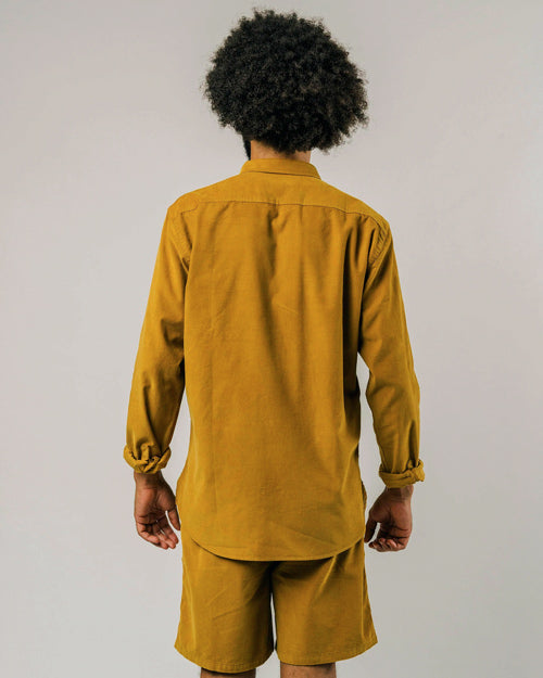 Photo d'un mannequin de dos portant une chemise velours pour homme en jaune moutarde et en coton bio fabriquée au Portugal.
