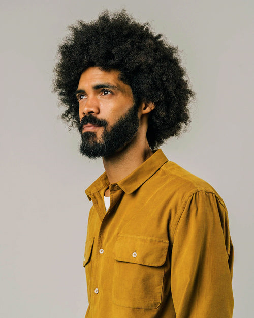 Photo zoomée sur le col d'une chemise velours pour homme en jaune moutarde et en coton bio fabriquée au Portugal.