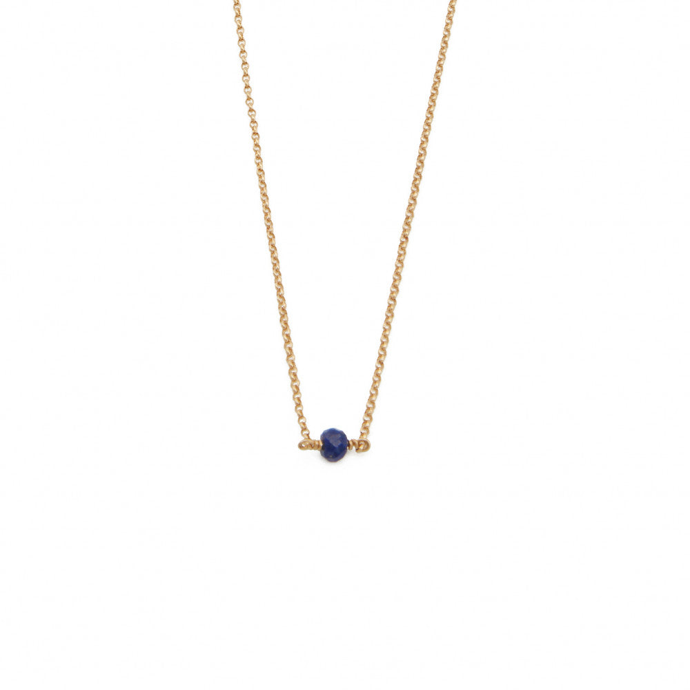 Photo sur fond blanc d'un collier fin doré avec une pierre lapis lazuli bleue et fabriqué en France.