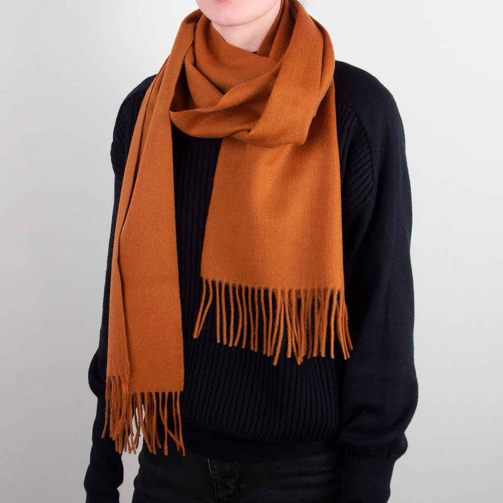 Photo d'une écharpe en laine avec des franges de couleur abricot portée par une femme.