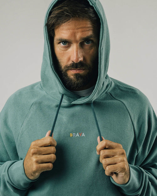 Photo d'un mannequin portant un hoodie brodé vert en coton bio et fabriqué au Portugal par Brava Fabrics.