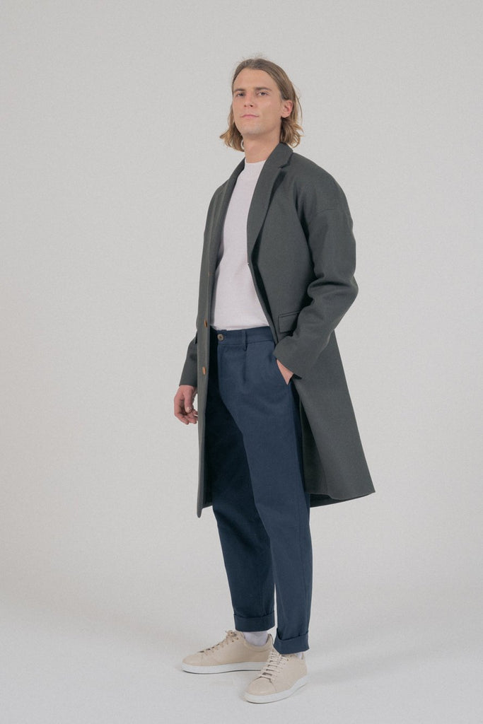 Un mannequin homme porte un manteau long oversize kaki de la marque Noyoco.