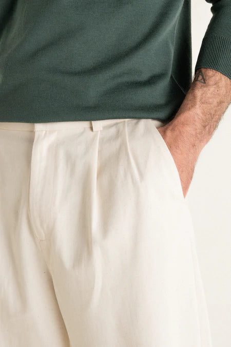 Photo zoomée d'un mannequin de profil portant un pantalon carotte taille haute écru en coton bio de la marque Noyoco.