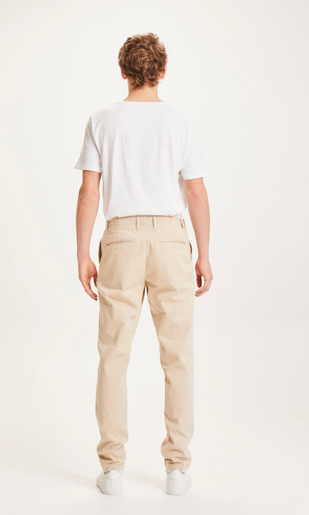 Photo d'un mannequin de dos portant un pantalon chino droit pour homme beige en coton bio de la marque knowledge cotton apparel.