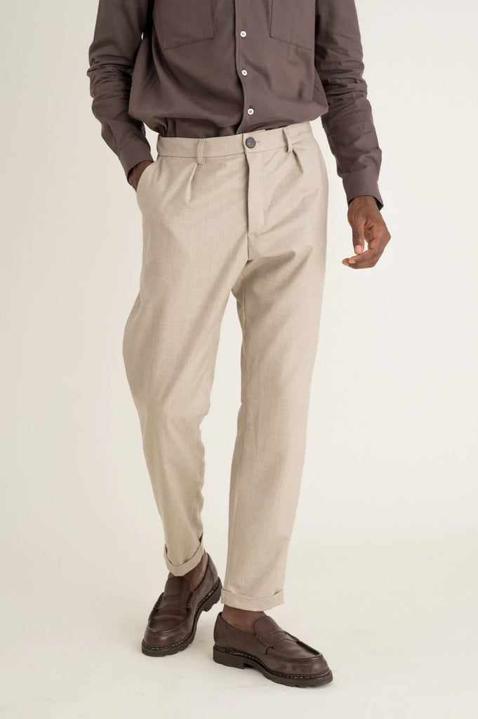 Un homme porte un pantalon à pince beige en laine vierge de la marque Noyoco