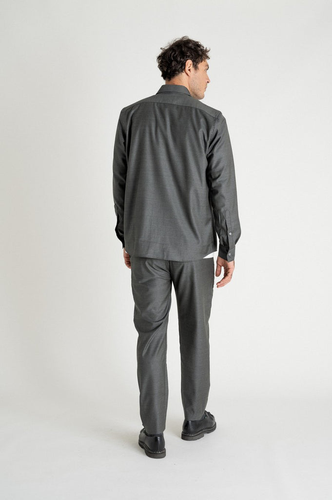 Un homme de dos porte un pantalon gris droit de la marque Noyoco.