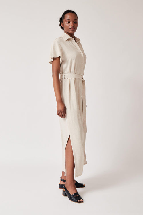 Photo d'un mannequin de profil portant une robe chemise ceinturée couleur crème en rayonne et lin et fabriquée en Espagne.