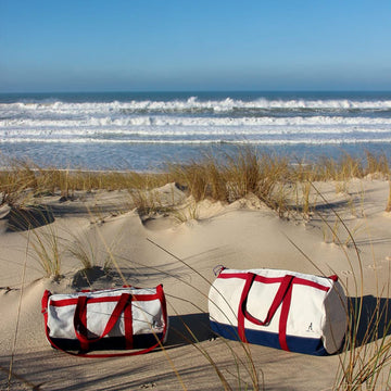 Photo sur la plage de deux sacs en voile de bateau de deux dimensions fabriqués en France.