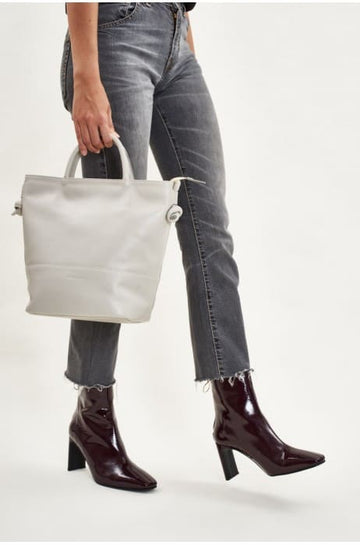 Photo d'un mannequin portant un sac rectangulaire à bandoulière écru en cuir de la marque espagnole Mint and Rose.