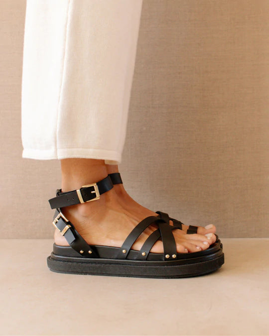 Phot d'une mannequin portant des sandales en cuir végétal noires vues de profil fabriquées en Espagne par Alohas.