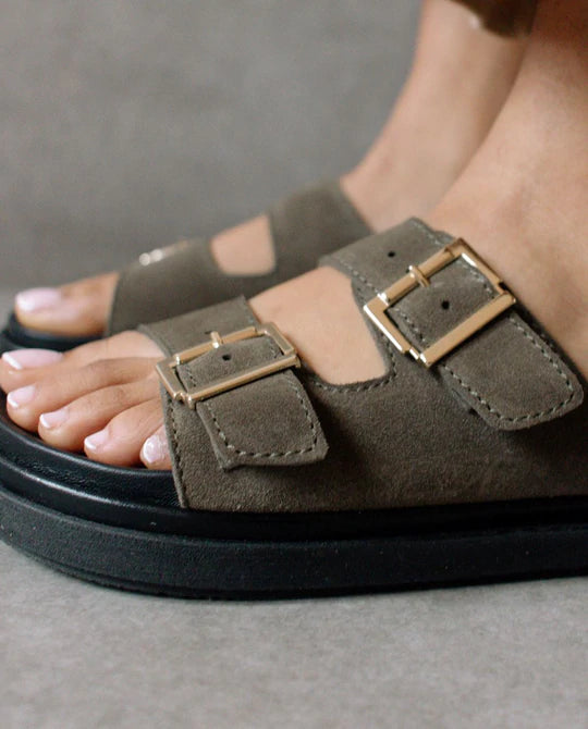 Photo zoomée sur les pieds d'un mannequin portant des sandales kaki  en daim certifié leather working group et fabriquées en Espagne par Alohas.