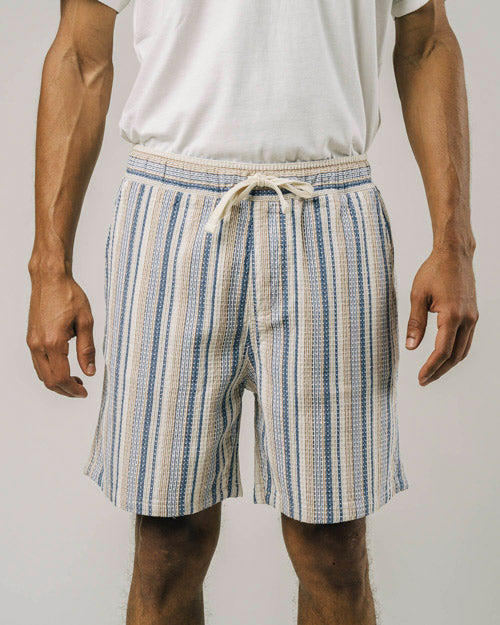 Photo d'un mannequin de face portant un short rayé pour homme aux couleurs beige, bleu et blanc en coton bio et fabriqué au Portugal.