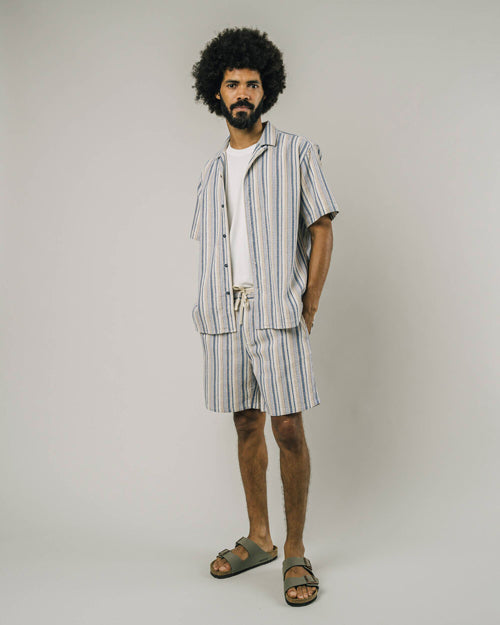 Photo d'un mannequin de face portant en total look un short rayé pour homme aux couleurs beige, bleu et blanc en coton bio et fabriqué au Portugal assorti à la chemise.