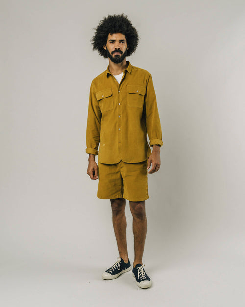 Photo d'un mannequin en total look moutarde portant un short en velours pour homme moutarde en coton bio fabriqué au Portugal.