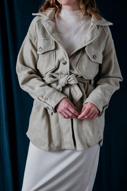 Photo d'un mannequin portant une surchemise beige ceinturée en coton bio fabriquée au Portugal de la marque Cossac. 