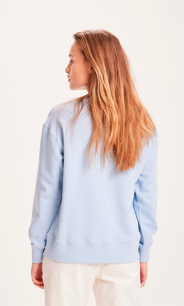Photo d'un mannequin de dos portant un sweat bleu ciel en coton bio de la marque knowledge cotton apparel.