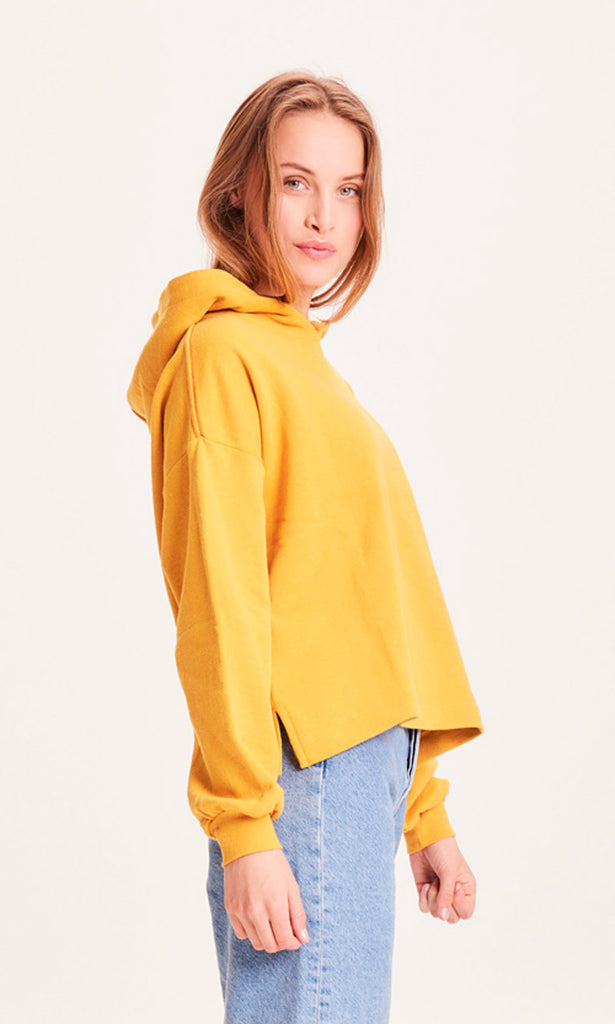 Photo d'un mannequin de profil portant un sweat coloré jaune en coton et polyester recyclés et fabriqué en Turquie.