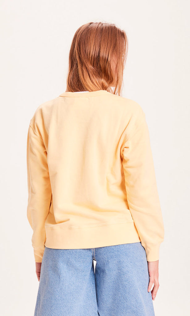 Photo d'un mannequin de dos portant un sweat jaune pastel pour femme en coton bio de la marque knowledge cotton apparel.