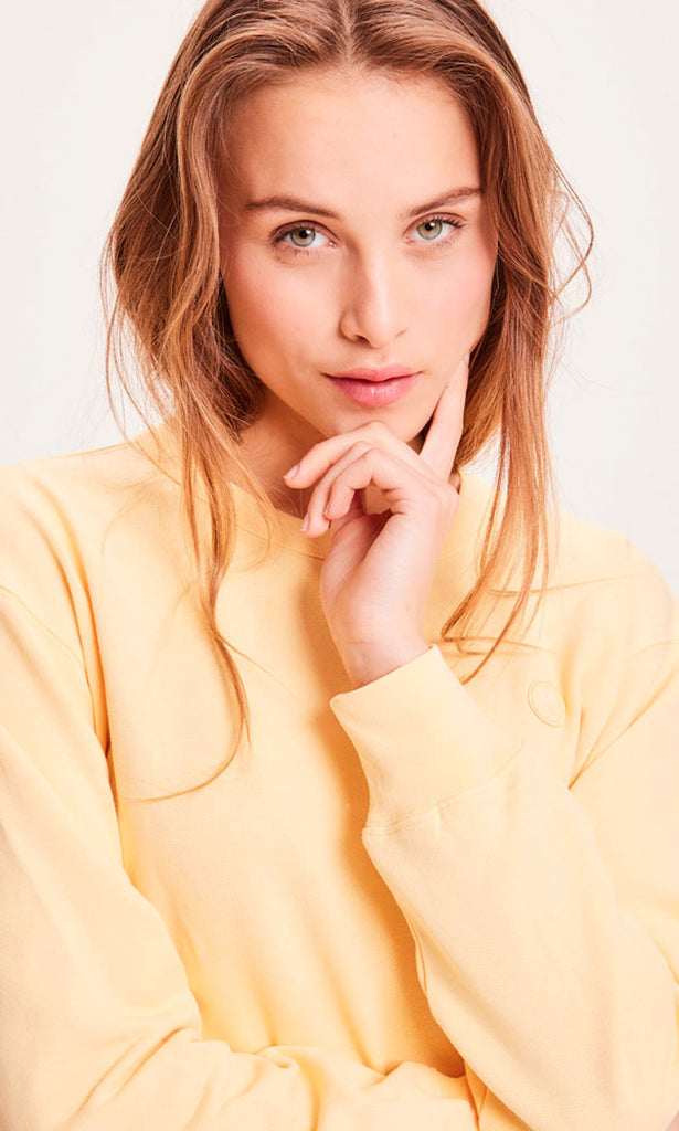 Photo d'un mannequin de face portant un sweat jaune pastel pour femme en coton bio de la marque knowledge cotton apparel.