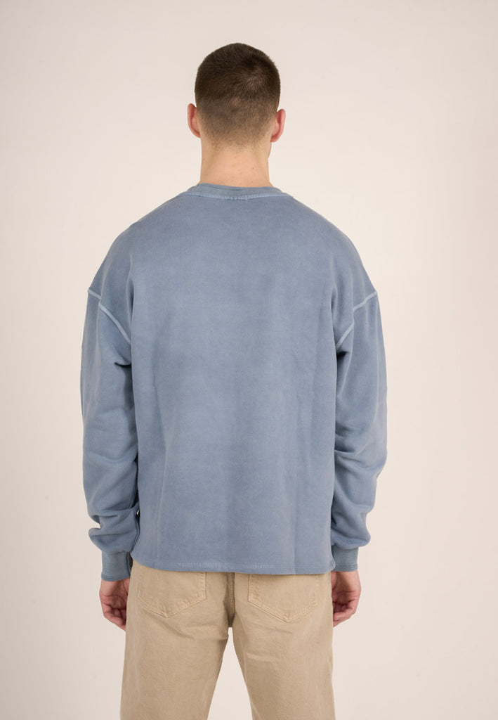 Photo d'un mannequin de dos portant un sweat oversize homme bleu gris teint naturellement en coton bio et fabriqué au Portugal.