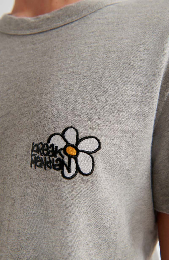 Photo zoomée d'un t shirt brodé d'une fleur gris en coton bio et fabriqué au Portugal.
