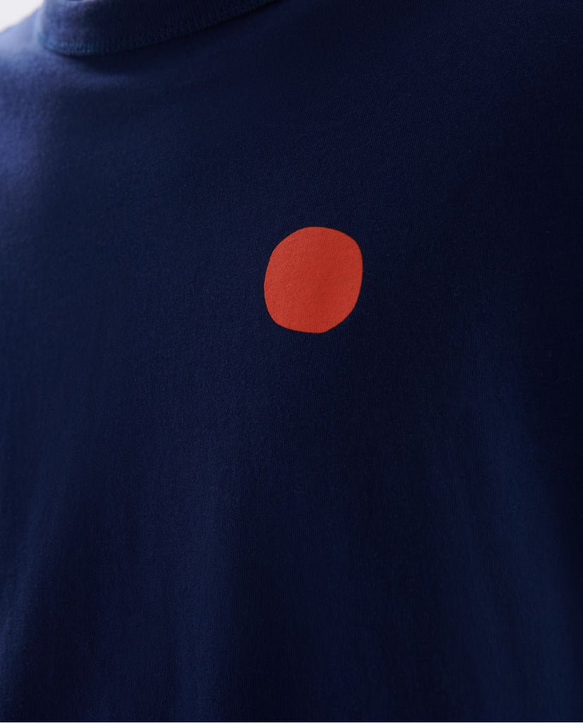 Photo zoomée d'un mannequin portant un t shirt en coton bio bleu marine avec rond rouge sur la poitrine et fabriqué au Portugal.