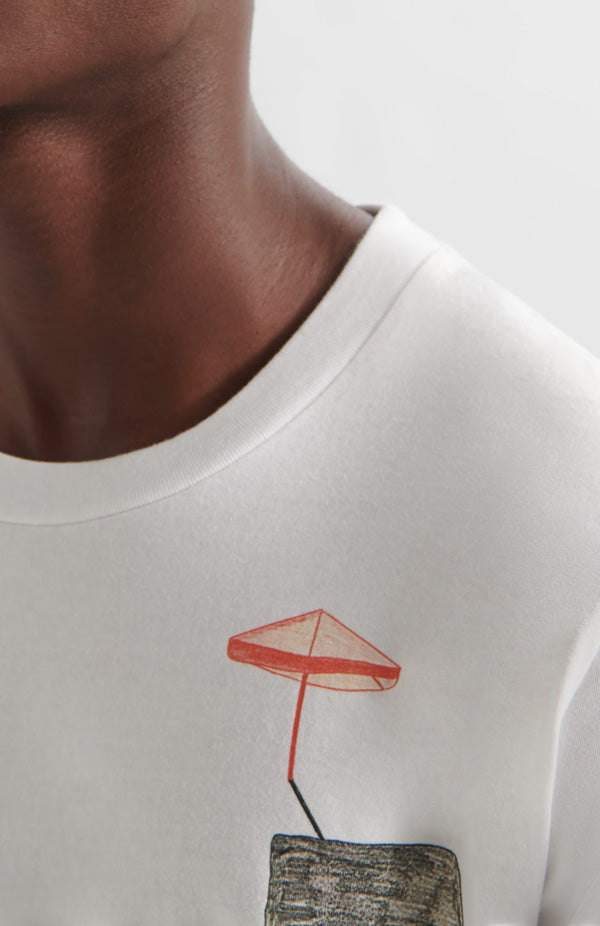 Photo zoomée d'un mannequin portant un t shirt en coton bio blanc avec un parasol imprimé sur la poitrine et fabriqué au Portugal.