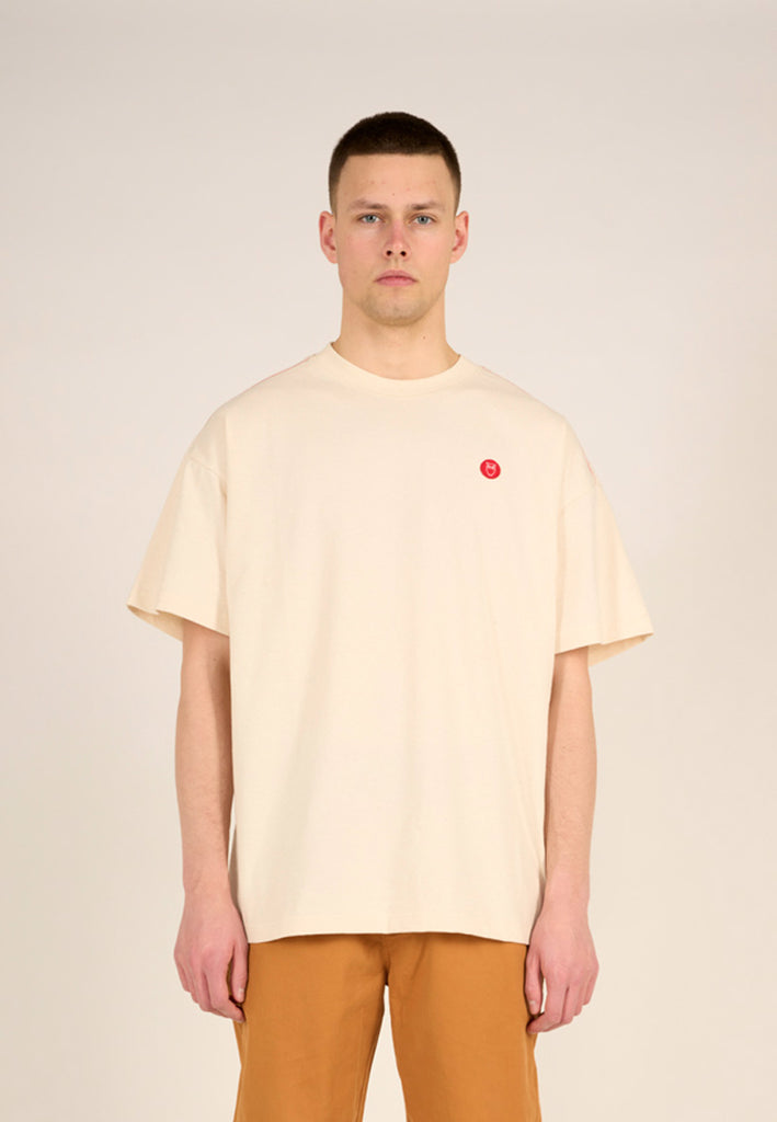 Photo d'un mannequin portant un t-shirt loose crème et fabriqué en Europe.