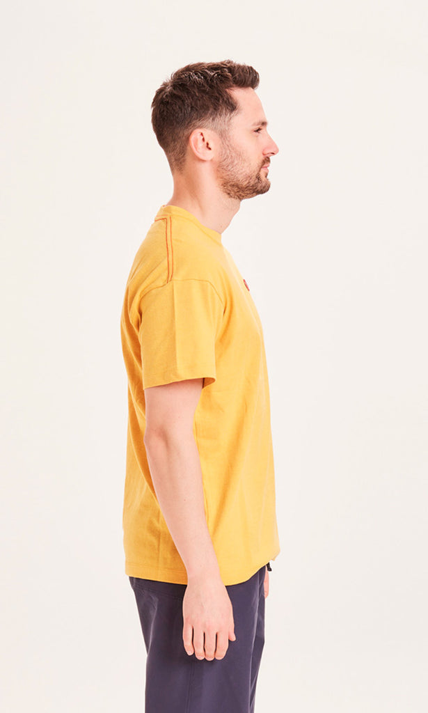 Photo d'un mannequin de profil portant un t-shirt recyclé jaune moutarde et fabriqué en Europe.