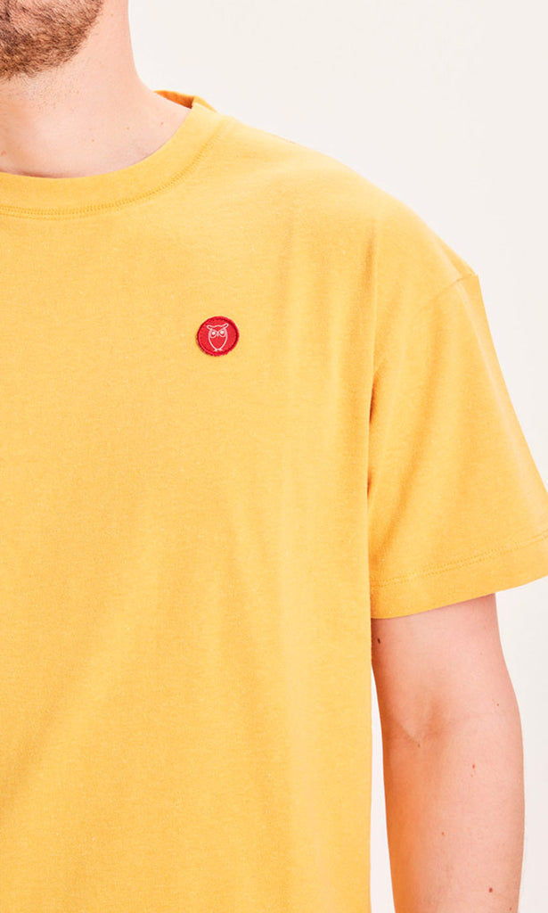 Photo zoomée d'un mannequin portant un t-shirt recyclé jaune moutarde et fabriqué en Europe.
