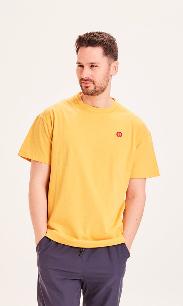 Photo d'un mannequin portant un t-shirt recyclé jaune moutarde et fabriqué en Europe.