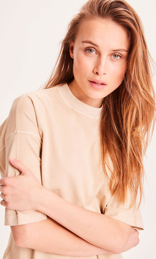 Photo de prêt d'une femme portant un t shirt en coton bio pour femme de couleur beige et teint naturellement. 