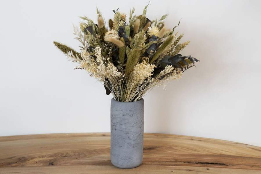 Photo d'un vase effet marbré en béton gris avec des fleurs séchées réalisé à la main par la Fabrik en France. 