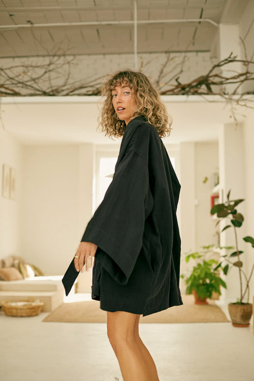 Photo d'un mannequin de profil portant une veste kimono pour femme noire en lyocell et fabriqué au Portugal.