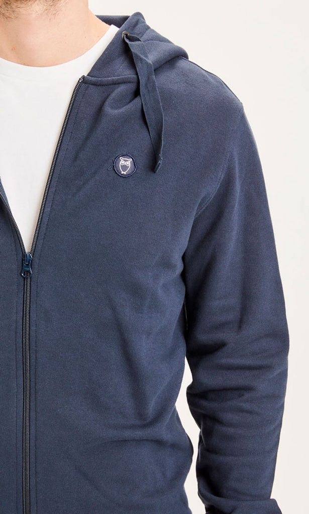 Photo zoomée d'un homme portant une veste zippée pour homme bleu marine en coton bio de la marque knowledge cotton apparel.