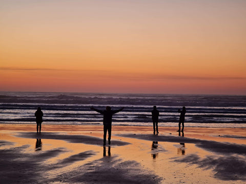 Photo de plusieurs personne de dos sur une plage à l'ile d'Oléron au couché du soleil.